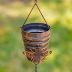 Rustic metal hanging planter with butterfly design against a blurred green background