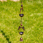 Decorative metal wind chime with angel wings against a green grass background