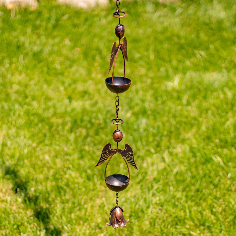 Decorative metal wind chime with angel wings against a green grass background