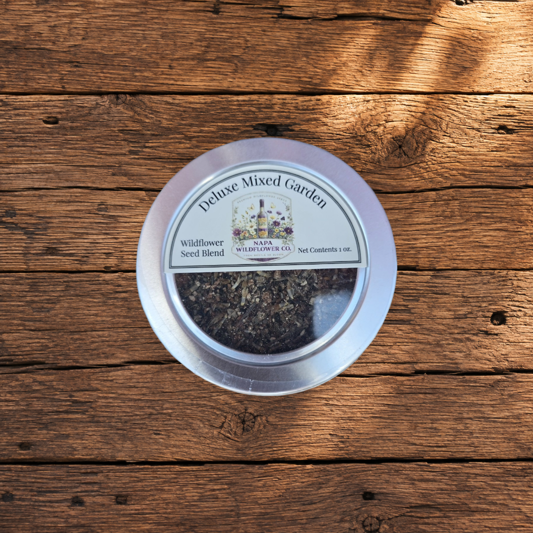 A round silver tin of Napa Wildflower Co. Deluxe Mixed Garden Seed Blend, shown from above on a rustic wooden plank background.