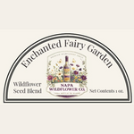 A product label graphic for Napa Wildflower Co. Enchanted Fairy Garden Wildflower Seed Blend, featuring a semi-circular border with floral and botanical illustrations in the center and text indicating the seed blend and 1 oz net contents.