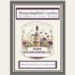 A framed vintage-style label or package design for Hummingbird Garden Wildflower Seed Blend, featuring a central bottle surrounded by illustrated wildflowers and butterflies, with the text 'NAPA WILDFLOWER CO.' and 'FROM BOTTLE TO BLOOM' on a cream background.