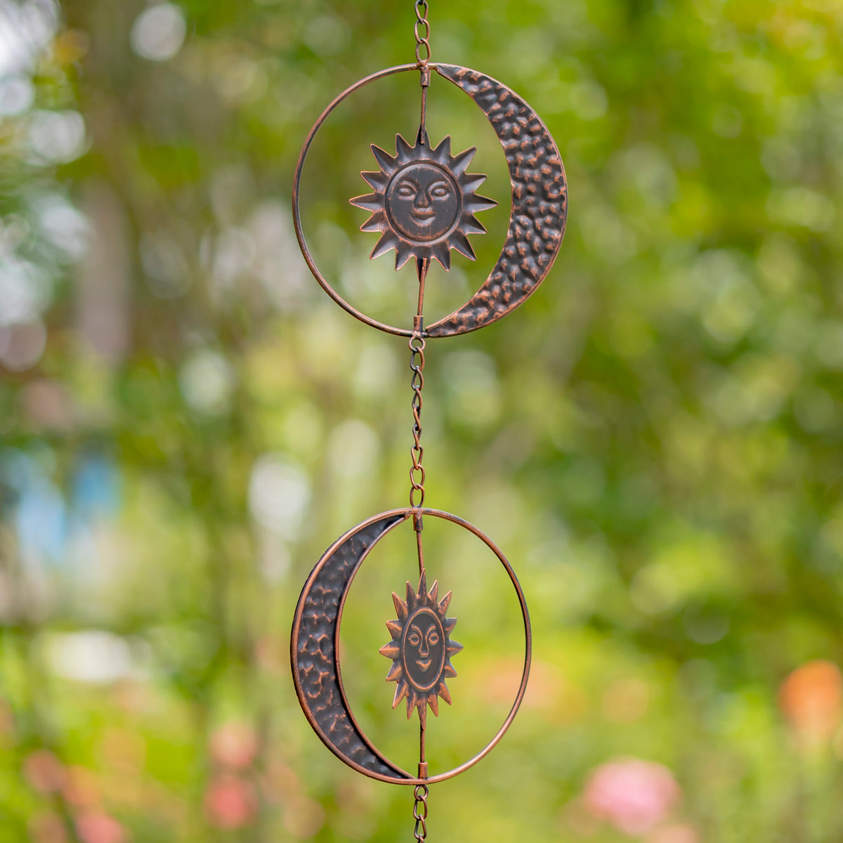 Decorative hanging with sun and moon designs against a blurred green background