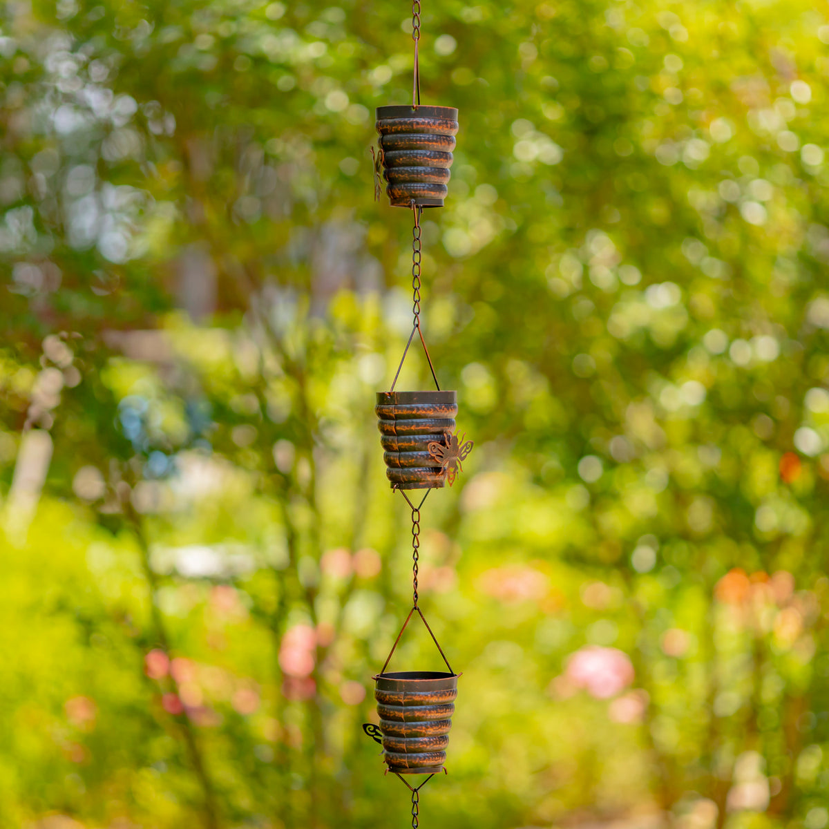 Decorative hanging planters with a blurred green garden background