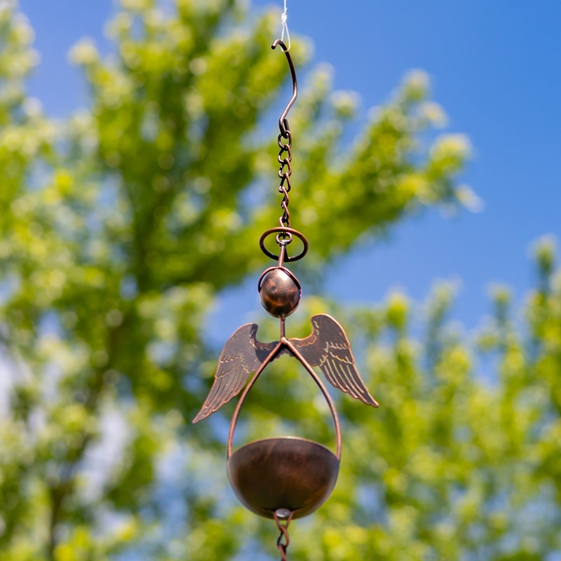 Decorative metal angel hanging ornament against a blurred natural background