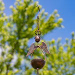 Decorative metal angel hanging ornament against a blurred natural background