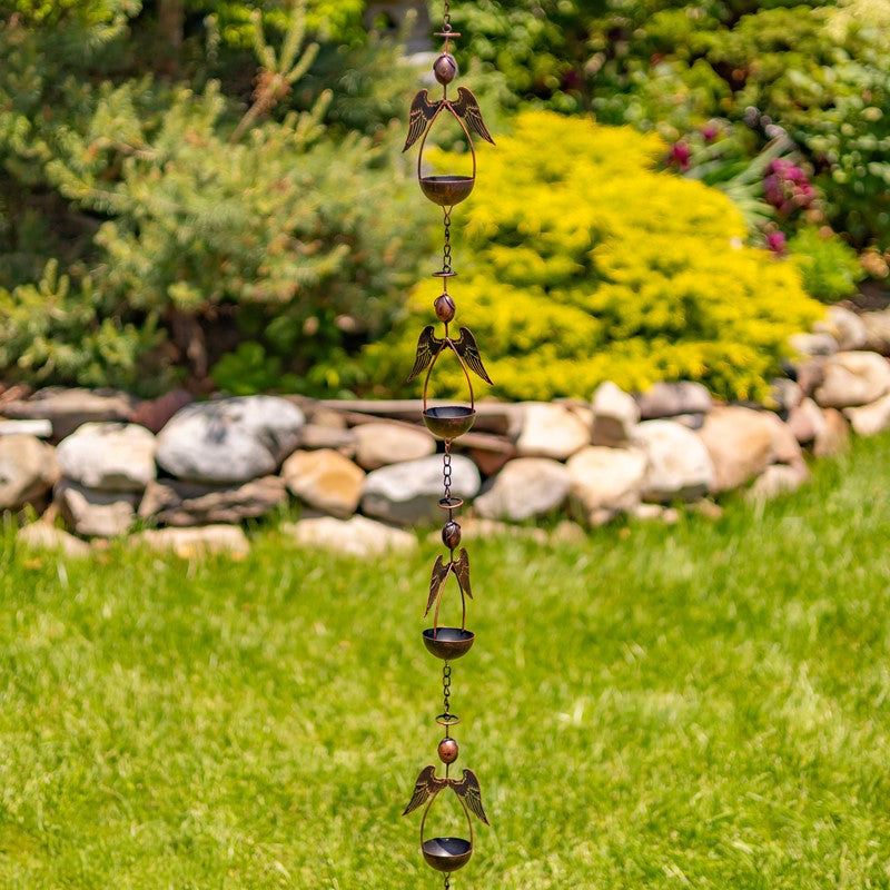 Decorative wind chime in a garden setting with green grass and rocks.