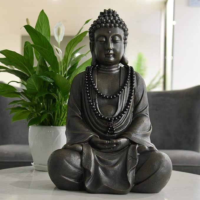 Buddha statue with beads on a table with plants and a couch in the background