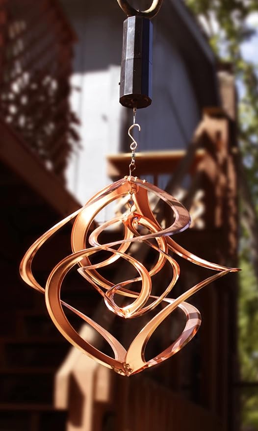 Copper wind chime hanging outdoors with a blurred background