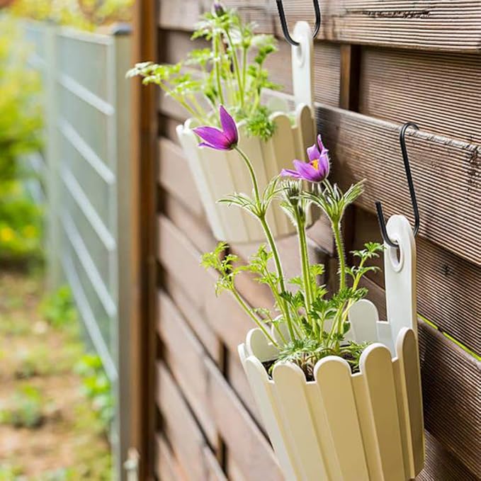 White vertical garden with purple flowers attached to a wooden fence