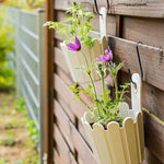 White vertical garden with purple flowers attached to a wooden fence