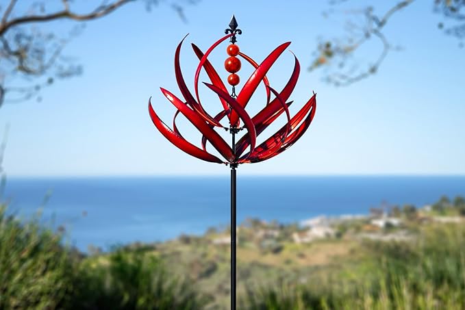 Red decorative garden stake against a scenic background with ocean and sky.