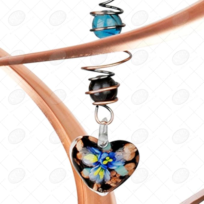 Heart-shaped glass ornament with floral design hanging from a copper spiral on a white background