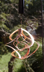 Decorative metal wind chime hanging against a blurred natural background