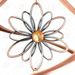 Decorative metal flower with a central orange gem on a white background