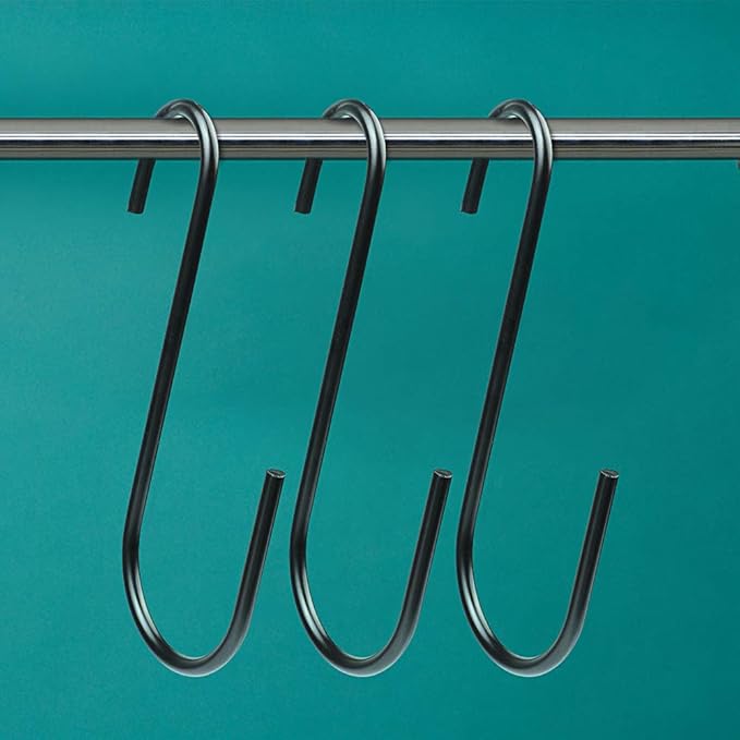 Black S-hooks hanging on a metal rod against a teal background