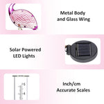 Solar-powered LED light with metal body and glass wing, inch/cm accurate scales, and solar panel on a pink background.