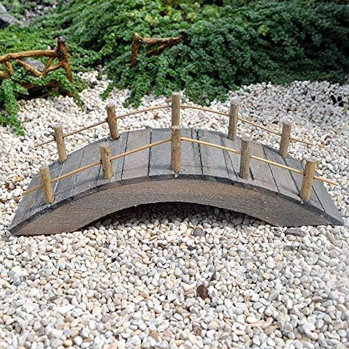 Small wooden bridge on a pebble surface with greenery in the background
