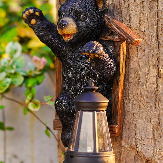 Black bear figurine with a lantern attached to a tree