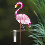 Pink flamingo garden stake with a ruler for scale against a green plant background