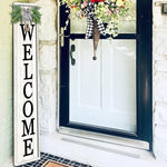 Decorative 'WELCOME' sign on a door with floral decorations.