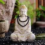 Statue of a meditating Buddha with beads in a garden setting