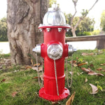 Red fire hydrant with silver details on grass near a tree