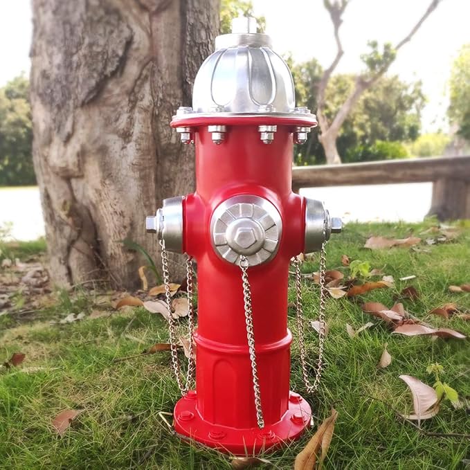 Red fire hydrant with silver details on grass near a tree