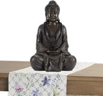 Bronze Buddha statue on a floral tablecloth with a white background
