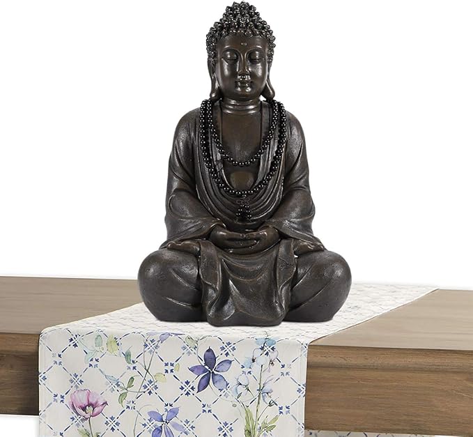 Bronze Buddha statue on a floral tablecloth with a white background