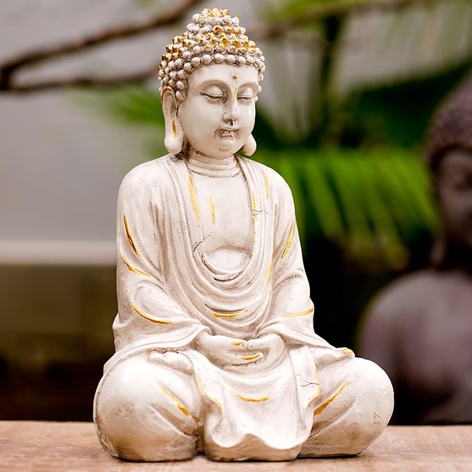 White Buddha statue with gold accents on a wooden surface