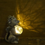 Decorative dragon lamp with a glowing orb on a textured surface