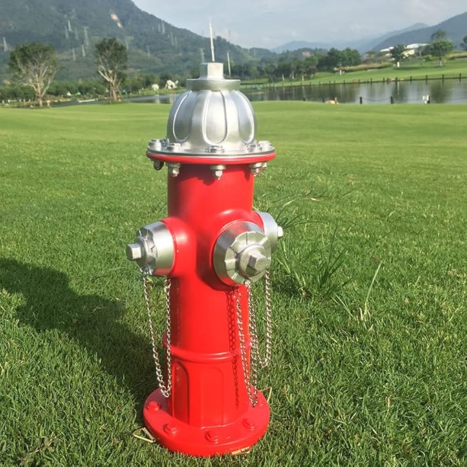 Red fire hydrant with silver components on a grassy field with mountains in the background