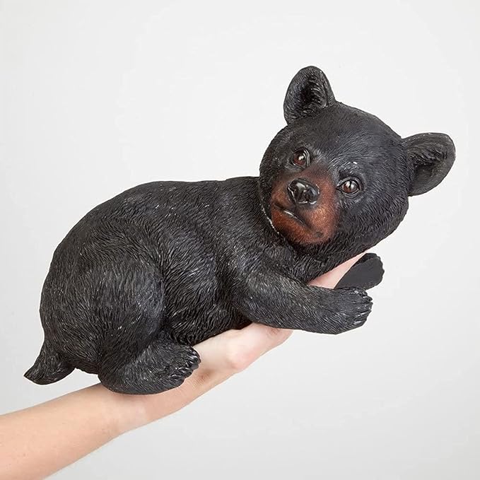 Black bear figurine held in a hand against a light gray background