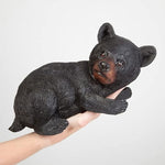 Black bear figurine held in a hand against a light gray background
