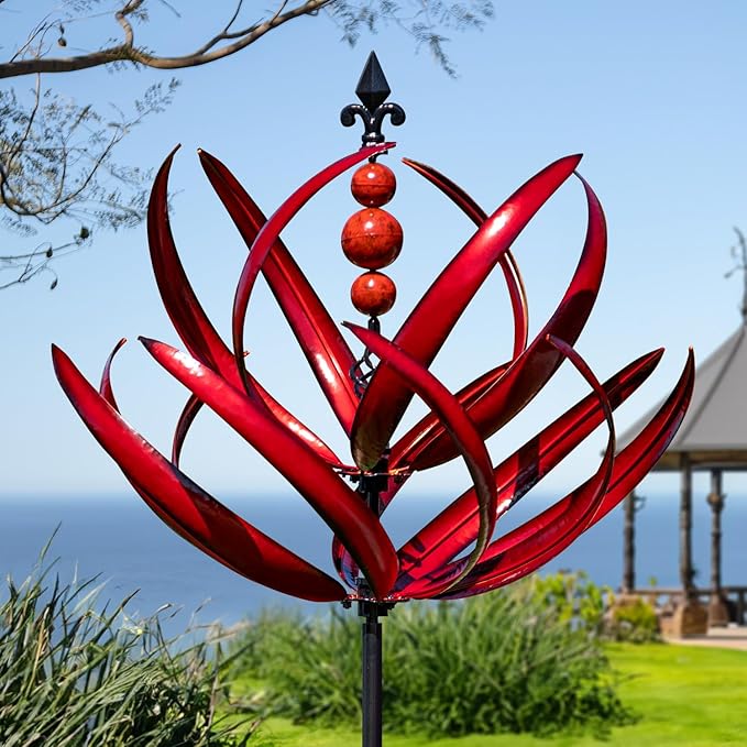 Red metal garden sculpture with a blue sky and ocean background