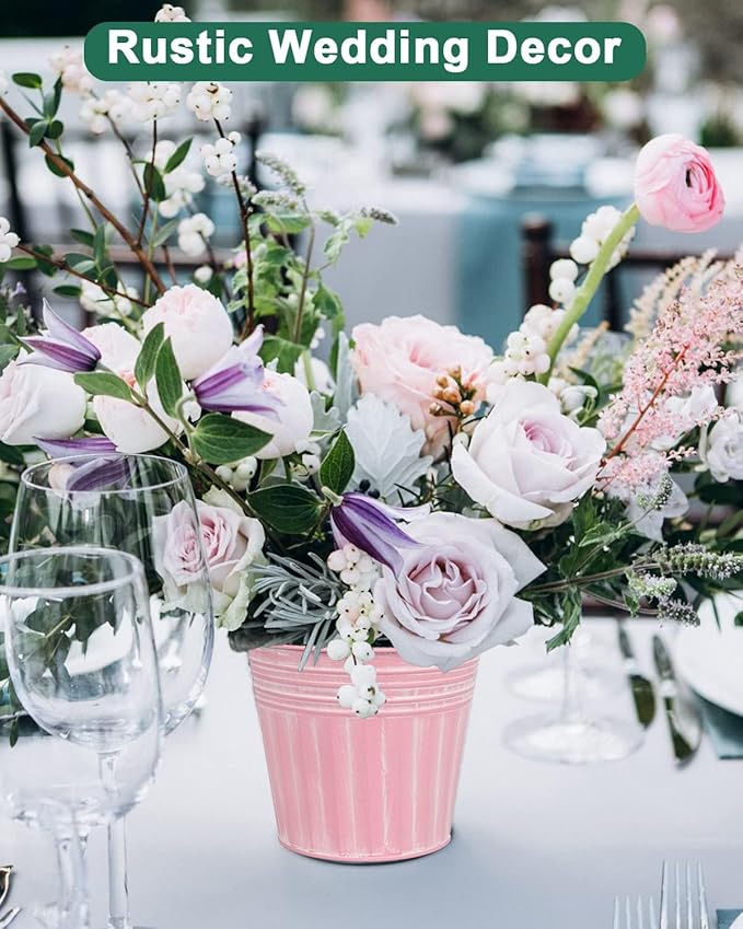 Floral arrangement in a pink bucket with glasses on a table, labeled 'Rustic Wedding Decor'.