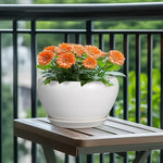 White planter with orange flowers on a wooden table outdoors