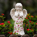 Statue of an angel with floral design in a garden setting