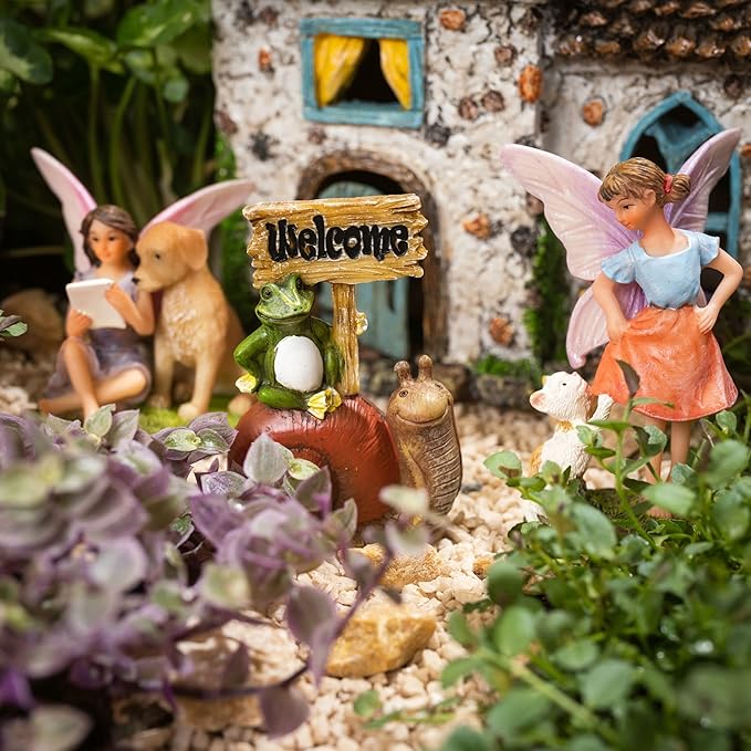 Fairy garden with miniature figures, a 'Welcome' sign, and a small house.