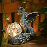 Dragon-shaped solar light with a glowing ball on a wooden surface