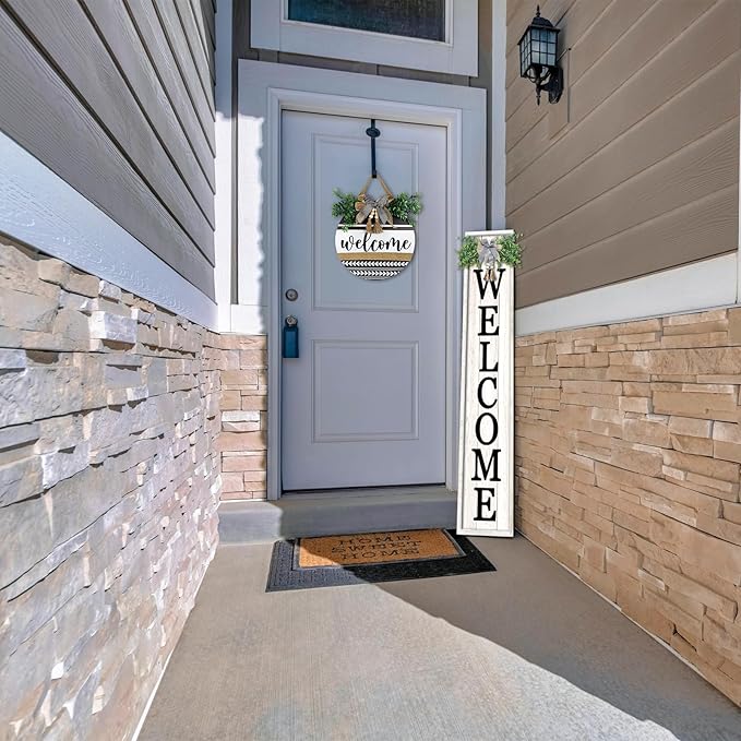 Front door of a house with a welcome mat and a large vertical welcome sign.