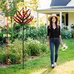 Woman standing next to a tall red garden sculpture with measurements, in a garden setting.