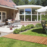 Garden with wooden deck, patio furniture, and a house in the background