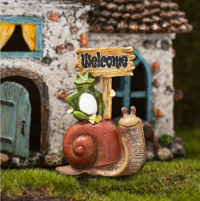 Decorative garden figurine with a snail, frog, and 'Welcome' sign in front of a miniature house.