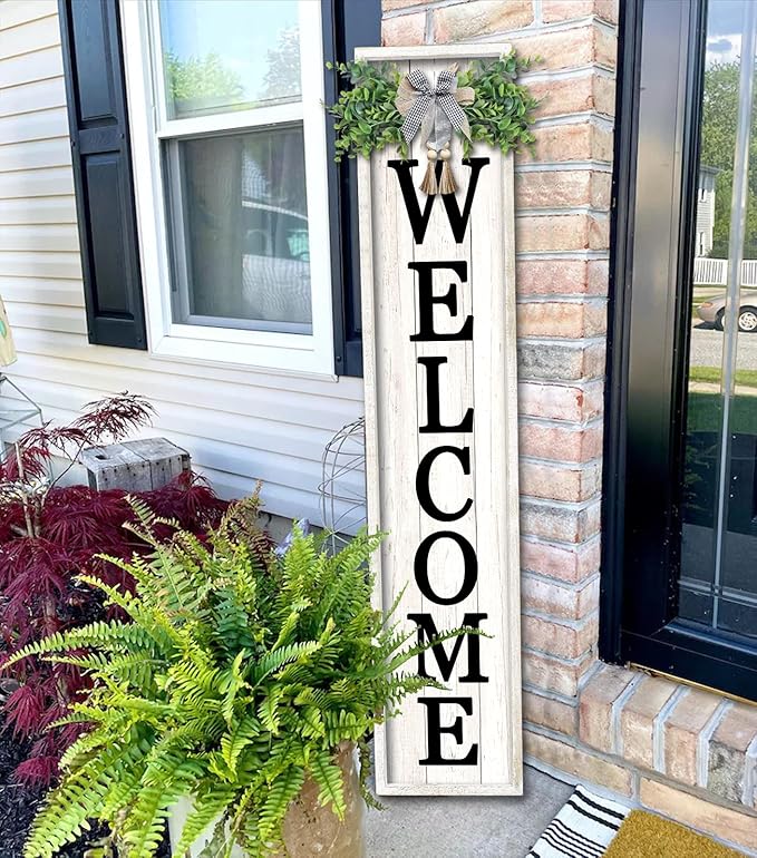 Decorative 'WELCOME' sign on a house exterior with plants and a window.