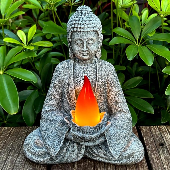 Statue of a Buddha holding a glowing orange light against a green leafy background