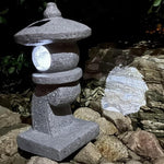 Stone lantern-style light fixture on a rocky surface with a dark background