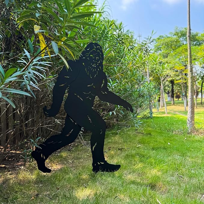 Black silhouette of a gorilla against a natural background with trees and grass.