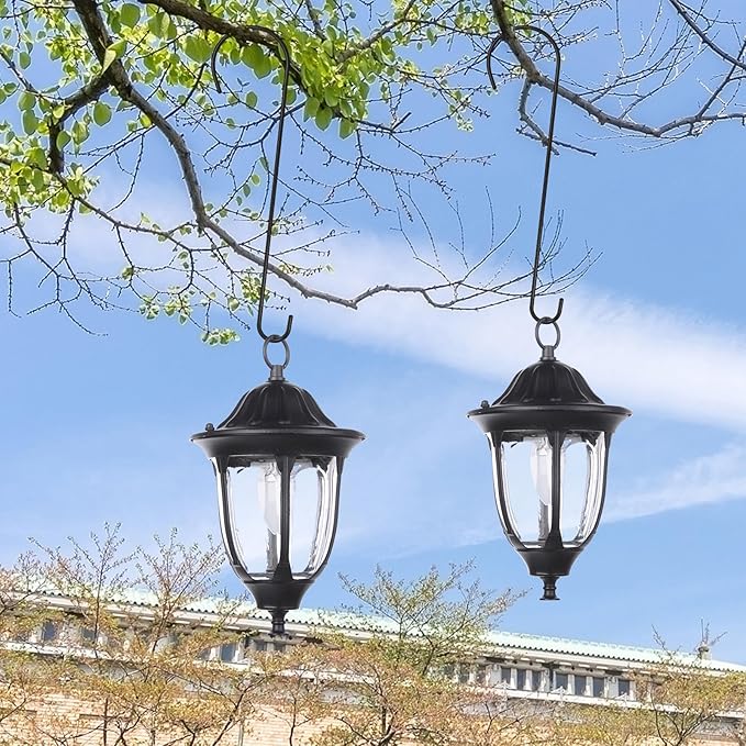 Two black outdoor hanging lanterns with clear glass against a blue sky.